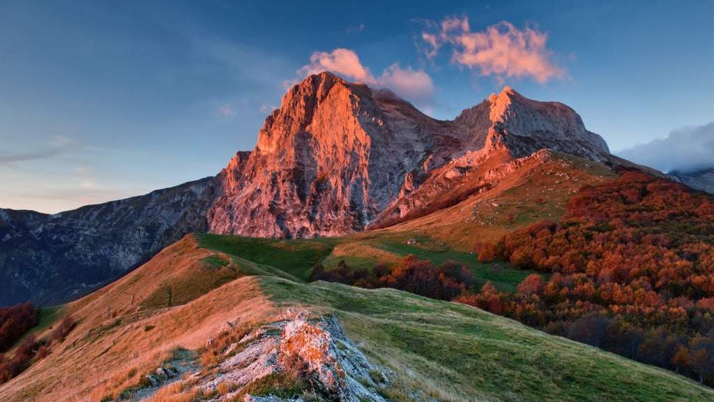 A scenic landscape view of the rugged Apennine mountain range stretching across the Italian peninsula under a bright sky.