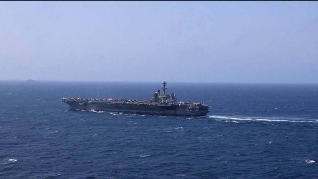 Commercial cargo ships navigating choppy waters near the Strait of Hormuz amid heightened regional maritime security tensions.
