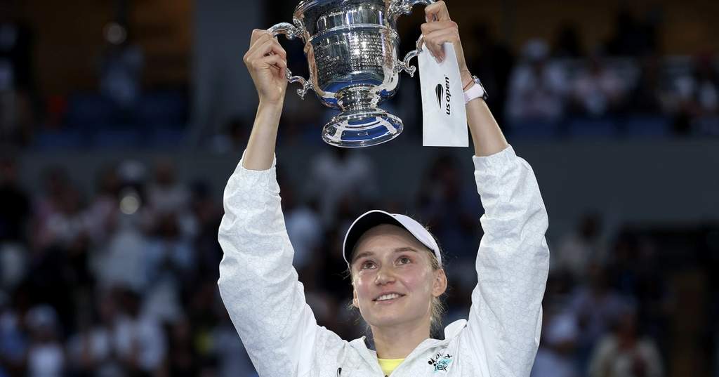 Tennis star Elena Rybakina holding up the championship trophy after defeating Aryna Sabalenka in the US Open women's final at Arthur Ashe Stadium.