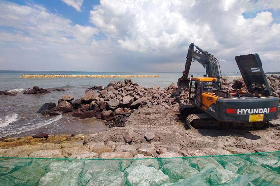 Heavy equipment working on coastal abrasion mitigation and infrastructure development in the Badung region of South Bali.