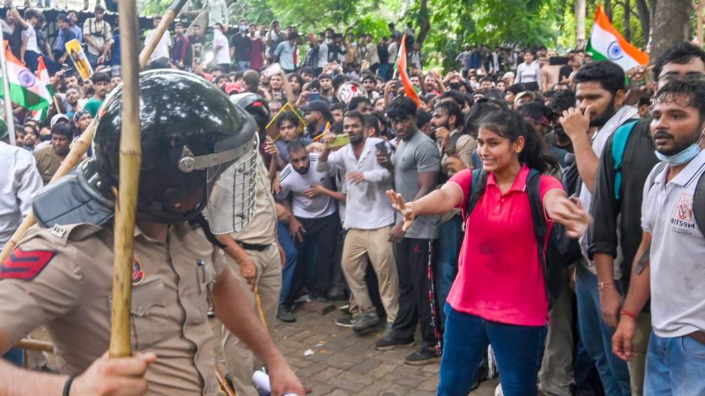 A large crowd of young Indian student protesters holding signs and rallying on the streets of New Delhi during demonstrations against exam leaks and unemployment.