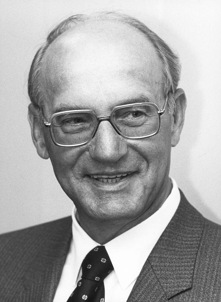 Archival photograph of computer scientist Nathaniel Rochester working alongside early IBM computing hardware and engineering blueprints.