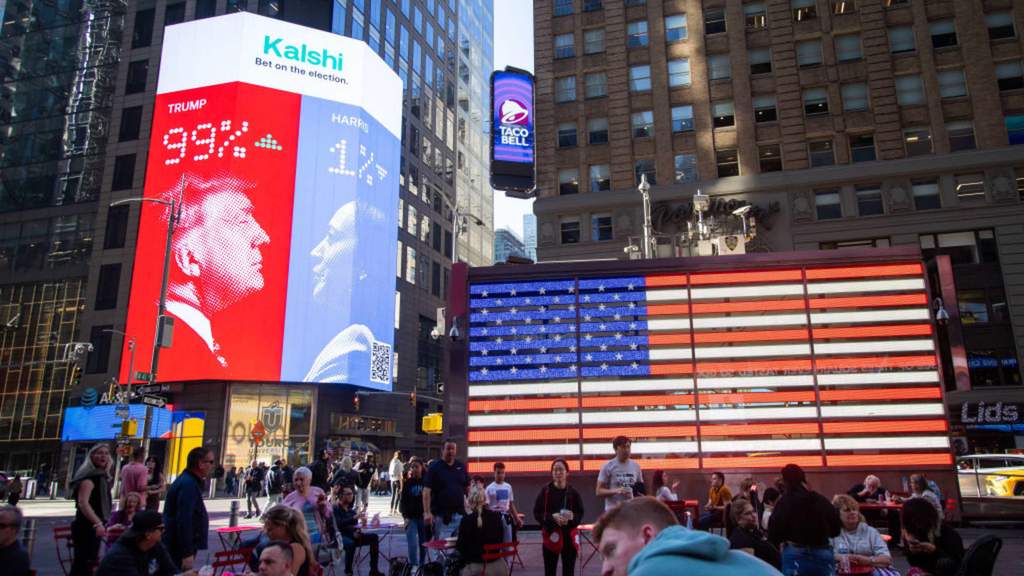Digital displays showing financial graphs and prediction market trading volumes alongside football and political campaign graphics.
