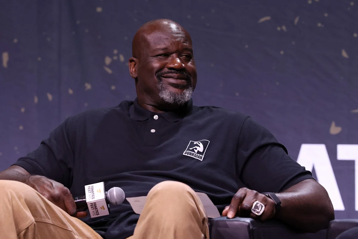 NBA legend Shaquille O'Neal speaking during a broadcast segment while wearing a dark suit and analyzing basketball games.