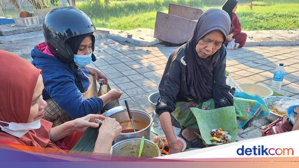 A long queue of local residents waiting patiently at a simple morning food stall near the Bintaro Fish Market entrance in Mataram, Lombok, to purchase wrapped Nasi Sasak.