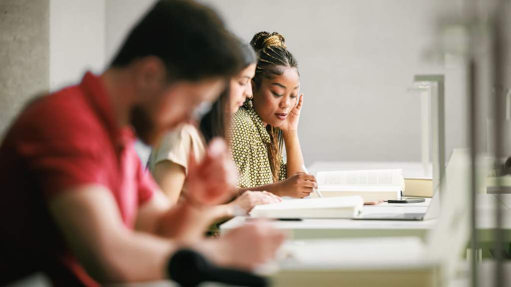 A college student reviewing education loan documents and financial aid statements at a desk, highlighting rising debt concerns under new regulations.